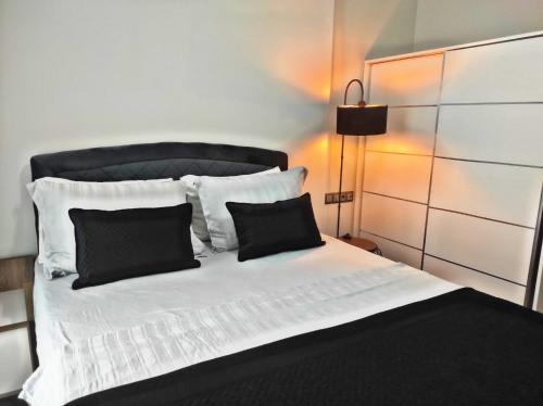 a bed with black and white pillows and a lamp at SABIHA GOKCEN HOTEL İSTANBUL HOUSES in Istanbul