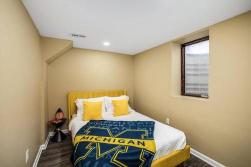 a bedroom with a king sized bed with yellow pillows at 10 Mins To The Big House and Sleeps Up To 10 Guests in Ann Arbor