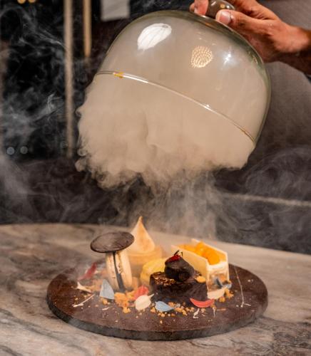 a person holding a pot over a cake with smoke at Regal Réseau Hotel & Spa in Negombo