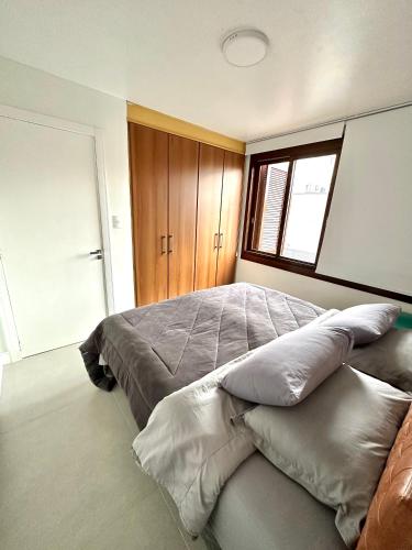 a bedroom with a large bed with pillows on it at Apartamento Artístico - Garagem - Ar Condicionado - Excelente Localização in Bento Gonçalves