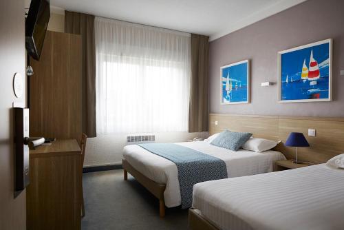 a hotel room with two beds and a window at The Originals City, Hôtel Les Océanes, Lorient in Lorient