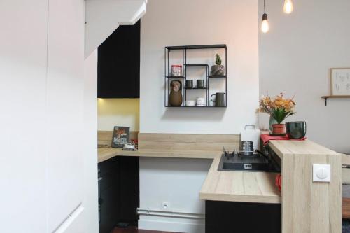 - une cuisine avec des murs blancs et des armoires noires dans l'établissement Atypical cocoon at the foot of Montmartre, à Paris