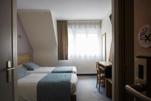 a hotel room with two beds and a window at The Originals City, Hôtel Les Océanes, Lorient in Lorient