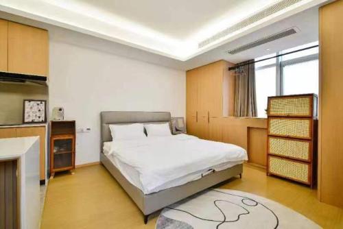 a bedroom with a large white bed and a kitchen at House of Great White Apartment in Shenzhen