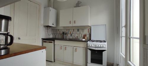 une cuisine avec des armoires blanches et un four à plaques de cuisson dans l'établissement Eole, à Wimereux