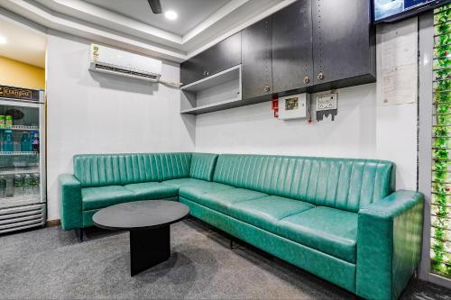 a green couch and a table in a room at FabHotel Saarthi Inn in Surat