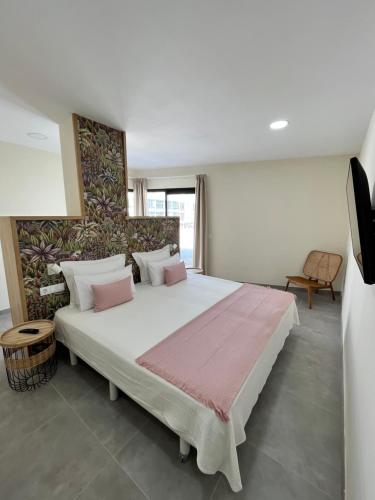 a bedroom with a large white bed with pink pillows at Arena Coral - Main Street - 50m Beach in Corralejo