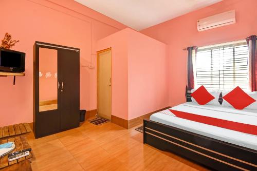 a room with two beds with red pillows and a window at Hotel O Adorini Guest House in Shānti Niketan