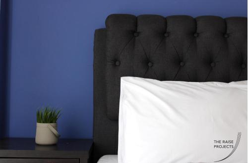 1 cama con almohada blanca y pared azul en Raise Limassol Urban Escape, en Limassol