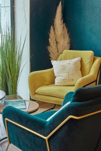 a living room with a yellow couch and a table at The Originals City, Hôtel Les Océanes, Lorient in Lorient