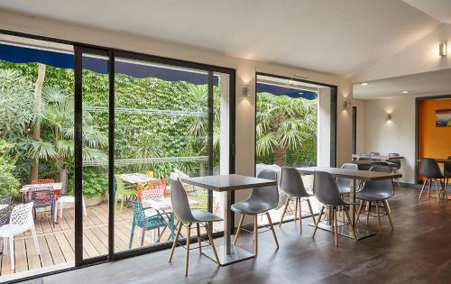 a restaurant with tables and chairs and large windows at The Originals City, Hôtel Les Océanes, Lorient in Lorient