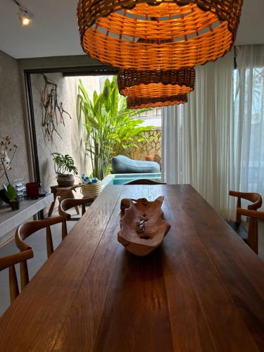 a dining room with a wooden table and a chandelier at Casa Nina Milagres in São Miguel dos Milagres