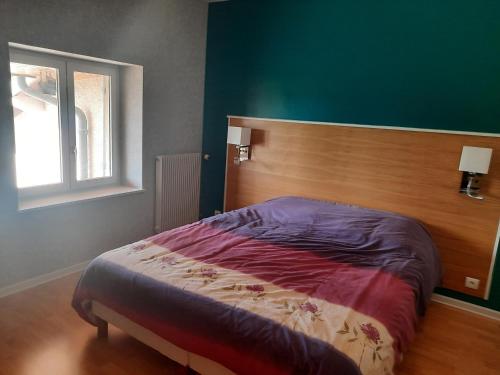 une chambre avec un lit avec une tête de lit en bois et une fenêtre dans l'établissement Maison au pied du Beaujolais, à Saint-Georges-de-Reneins