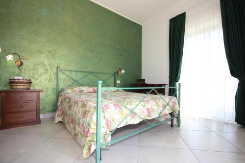 Laureana CilentoにあるAgriturismo Terra E Mareの緑の壁、ベッド付きのベッドルーム1室