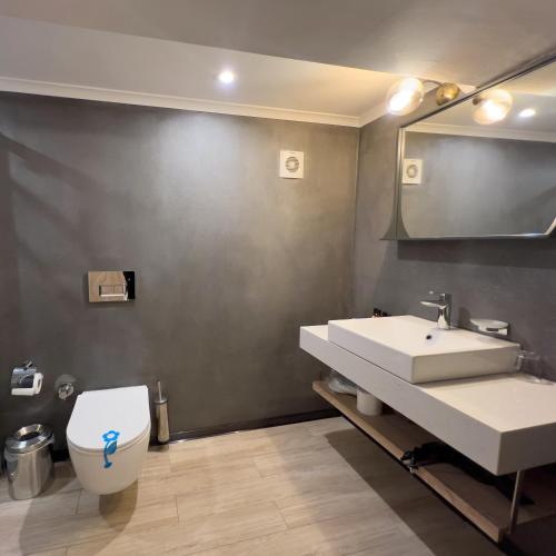 a bathroom with a sink and a toilet and a mirror at CUNDA PİER OTEL in Ayvalık