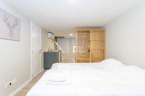 a white bedroom with a large bed and a kitchen at Studio1 Van Lerius in Antwerp