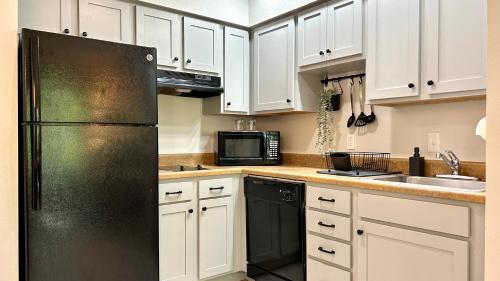 a kitchen with white cabinets and a black refrigerator at HSO - Family Apartments Close to Disney World & Universal in Orlando