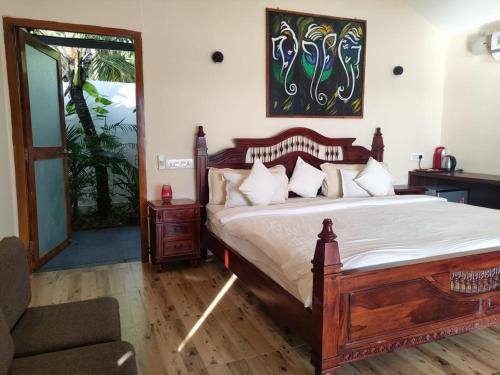 a bedroom with a large wooden bed and a chair at Agonda Beach Villa in Agonda