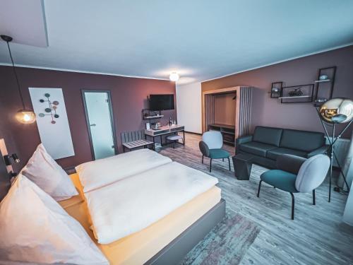 Habitación de hotel con cama y sofá en Restaurant Hotel Goldener Adler en Emden