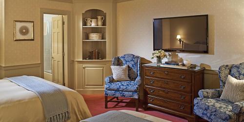 a bedroom with a bed and a dresser and a tv at Green Mountain Inn in Stowe