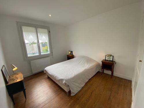 une chambre blanche avec un lit et une fenêtre dans l'établissement La maison bleue vacance et jardin, la mer à 550 m, à Blainville-sur-Mer