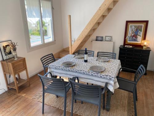 a dining room with a table with chairs and a staircase at La maison bleue vacance et jardin, la mer à 550 m in Blainville-sur-Mer
