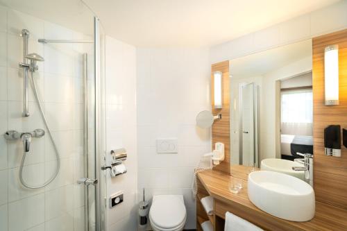 uma casa de banho com um WC, um lavatório e um chuveiro em Leonardo Hotel Vienna Schönbrunn em Viena