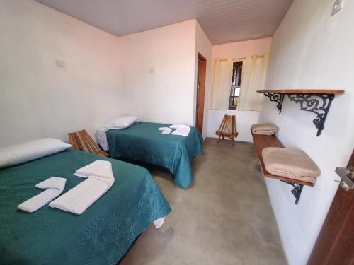 a room with two beds with towels on them at Pousada Trilhas de Gigantes in Itumirim