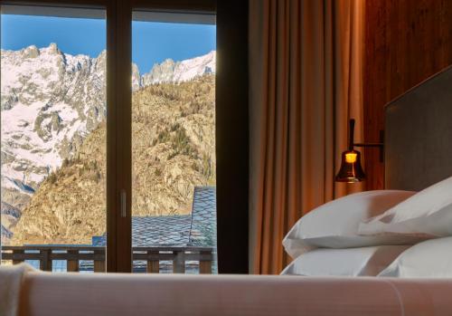 a bedroom with a window with a mountain view at Le Massif Hotel & Lodge Courmayeur The Leading Hotels of the World in Courmayeur