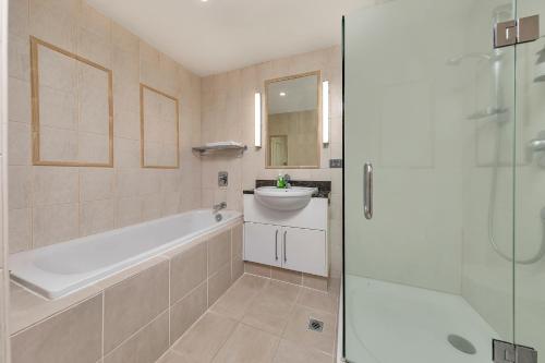 a bathroom with a tub and a sink and a shower at Exquisite Sun Soaked Corner Apartment in Auckland