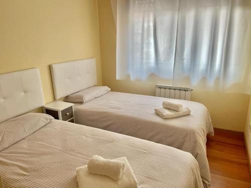 una camera con due letti e asciugamani di APARTAMENTO NUEVO ACOGEDOR a Mondariz-Balneario