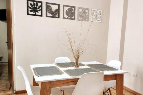 a dining room table with white chairs and pictures on the wall at Casita de Tucumán Apart - Cochera Cercana in San Miguel de Tucumán