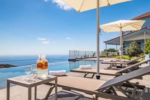 a patio with chairs and a table with a drink on it at Casas da Luz by Madeira Sun Travel in Ponta do Sol