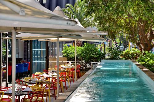 a swimming pool with tables and chairs next to a restaurant at Fountains Hotel in Cape Town