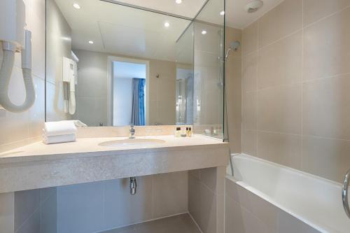 a bathroom with a sink and a tub and a mirror at Hôtel A La Villa des Artistes in Paris
