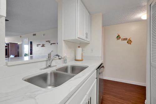 a kitchen with a stainless steel sink and white cabinets at Direct Oceanfront Condo Amazing Views Cocoa Beach in Cocoa Beach