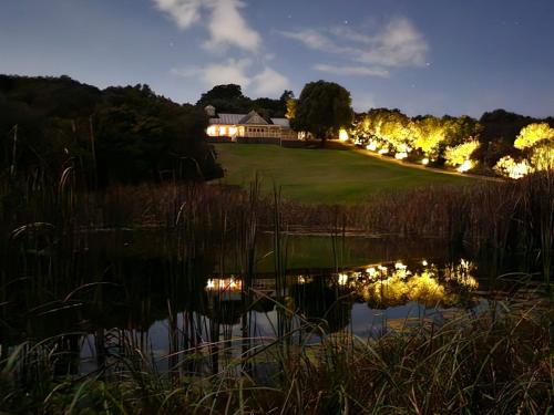 a house on a hill next to a pond at night at Die Heerenhuys Guest Suites in Stellenbosch