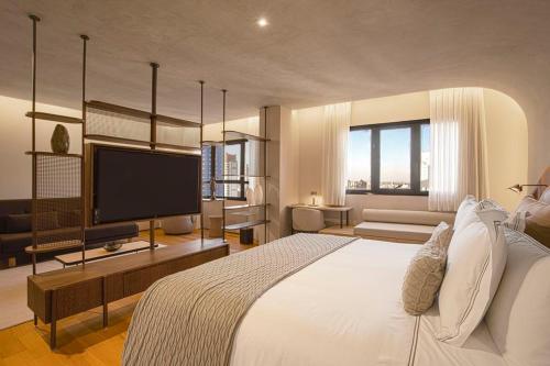 a bedroom with a large bed and a flat screen tv at QOYA Hotel Curitiba, Curio Collection by Hilton in Curitiba