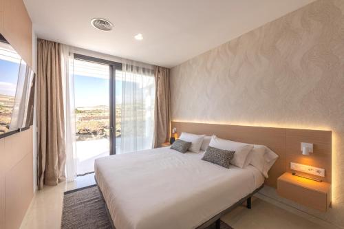 1 dormitorio con cama grande y ventana grande en Villa Andrea, quiet luxury, sunset with sea views, en Adeje