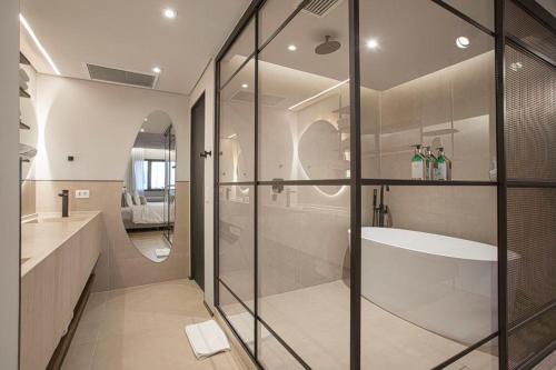 een badkamer met een glazen douche en een bad bij QOYA Hotel Curitiba, Curio Collection by Hilton in Curitiba