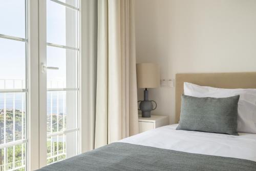 ein Schlafzimmer mit einem Bett und einem großen Fenster in der Unterkunft Casas da Luz by Madeira Sun Travel in Ponta do Sol