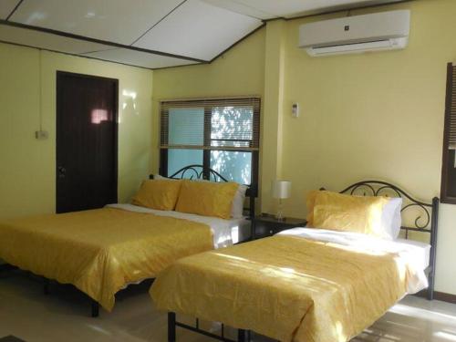 a bedroom with two beds with yellow sheets and a window at Guest House, shared pool, private bathroom and kitchen in Phuket