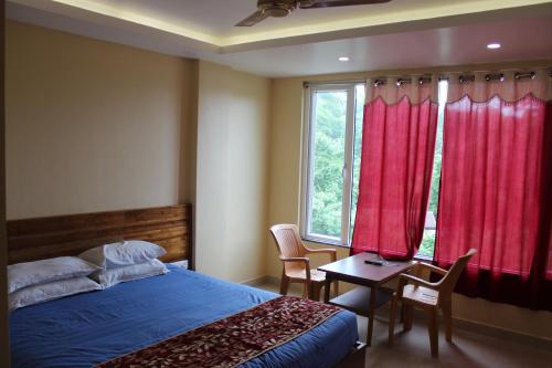 a bedroom with a bed and a table and a window at White Coral in Port Blair