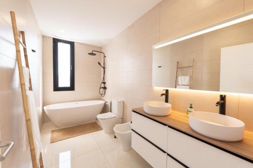 a bathroom with two sinks and a tub and a toilet at Villa Andrea, quiet luxury, sunset with sea views in Adeje