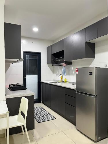 Il comprend une cuisine équipée d'un réfrigérateur en acier inoxydable et d'une table. dans l'établissement Reizz Residence by AFFDECH, à Kuala Lumpur