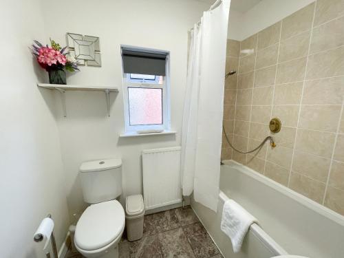 a white bathroom with a toilet and a bath tub at Large House near MediaCity, sleeps 13 with FREE Parking and Fast WIFI - Contractor and Long Stay Friendly - by IRWELL STAYS in Manchester