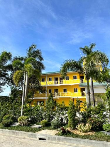 un edificio giallo con palme di fronte di Dreaming Forest Hotel - Libjo, Batangas a Città di Batangas