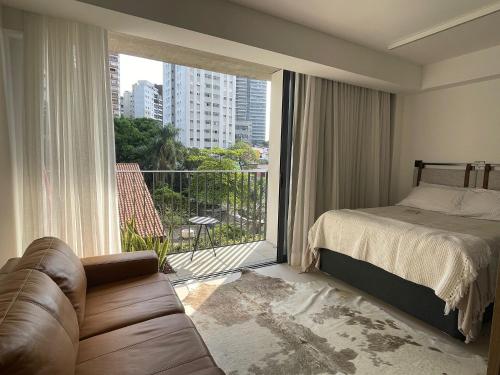 a bedroom with a bed and a couch and a large window at Vossa bossa Vila Madalena in Sao Paulo