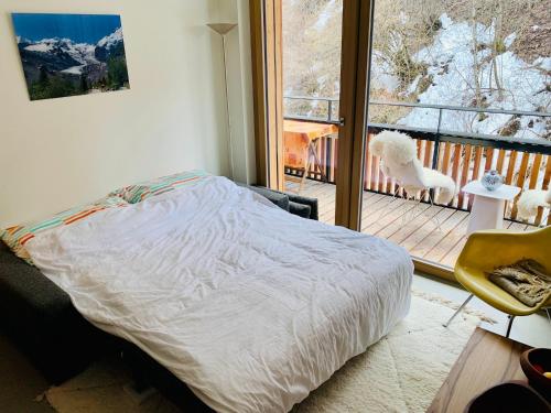 a bed in a room with a view of a balcony at Sunny Stenna Selva 3-room ski-in ski-out apartment right by the slopes & lifts in Flims