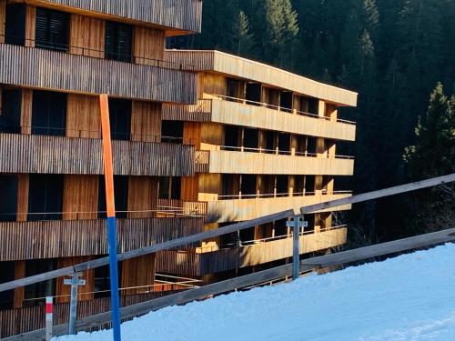 a building in the snow with a fence in front of it at Sunny Stenna Selva 3-room ski-in ski-out apartment right by the slopes & lifts in Flims